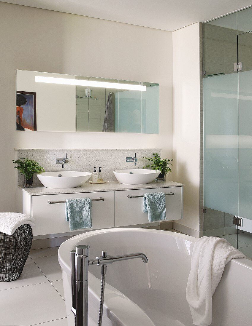 Elegant bathroom with bathtub, washstand with twin sinks and glazed shower area