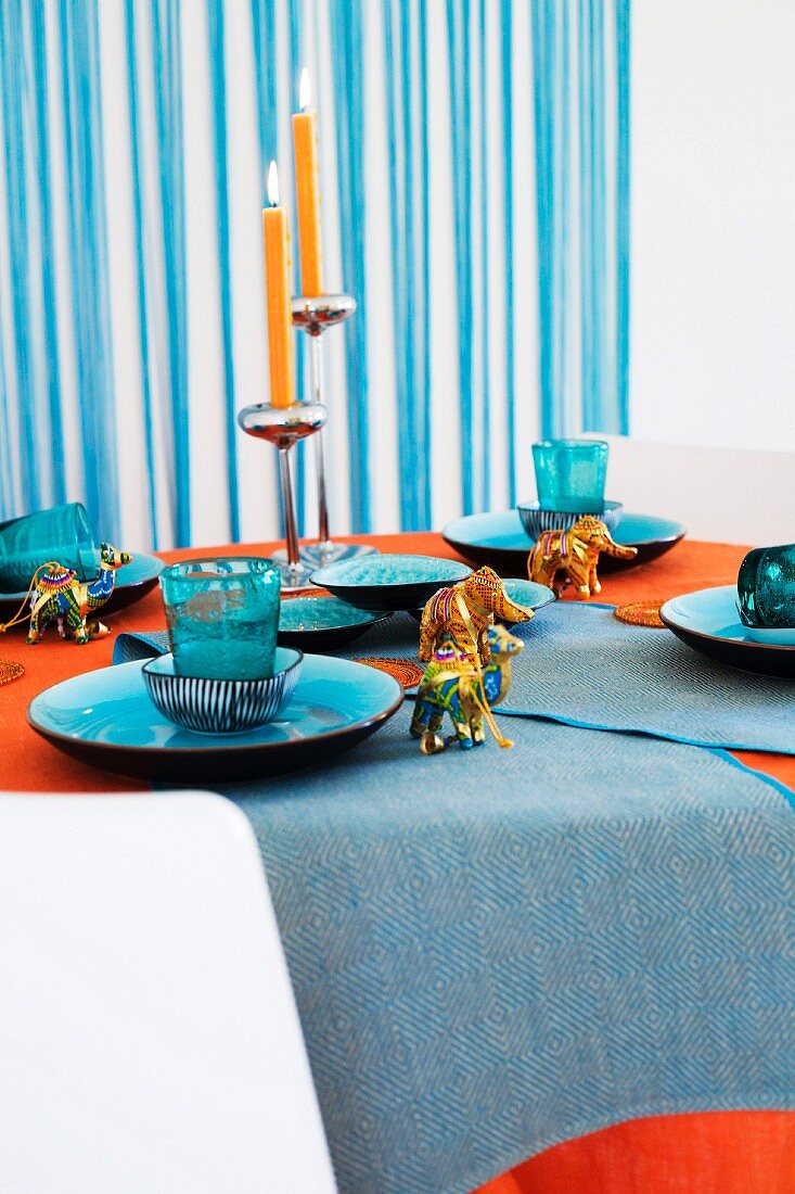 Gedeckter Tisch mit blauem Geschirr, mit kleinen Elefanten- und Tierfiguren und Kerzenständer