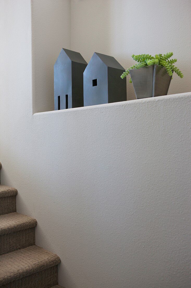 Zimmerpflanze und Holzhäuschen als Dekoration in Wandnische an Treppenaufgang
