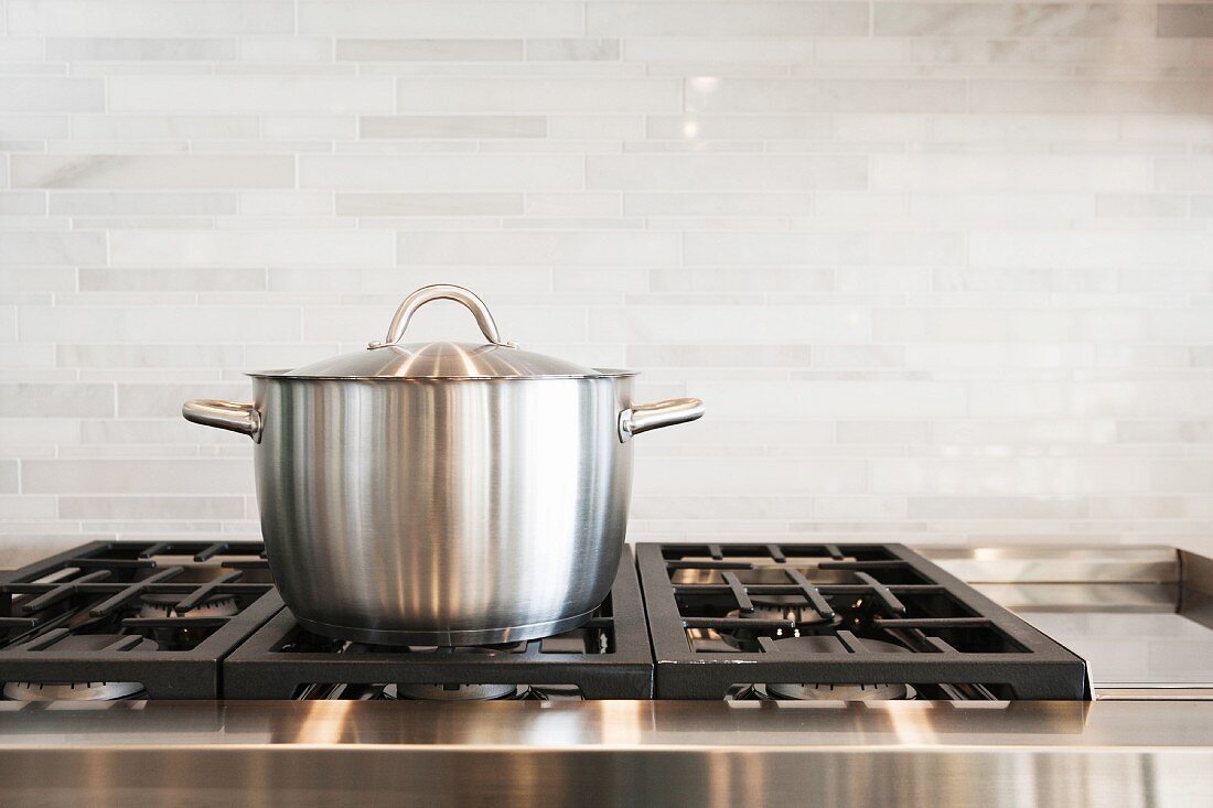 Saucepan on hob with splashback in kitchen