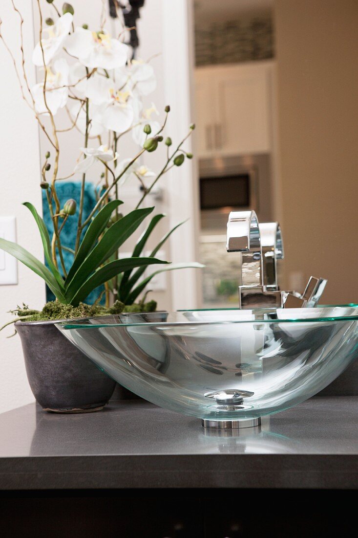 Moderner Waschtisch mit Waschschale aus Glas & Orchideen als Blumendeko
