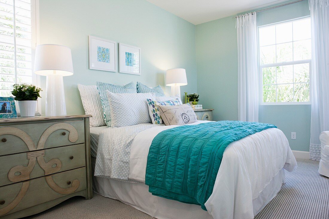 Schlafzimmer in Blautönen mit Doppelbbett, Kommoden als Nachttischen und Tischleuchten