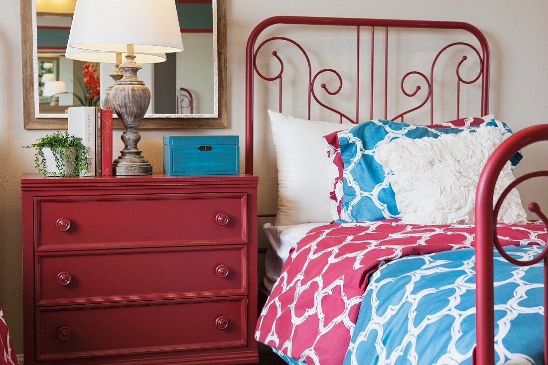 Schlafzimmer mit rotem Metallbett & roter Kommode als Nachttisch