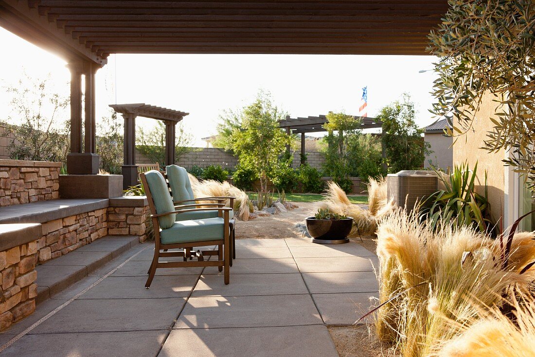 Überdachte Terrasse mit Stühlen & dekorativer Grasbepflanzung