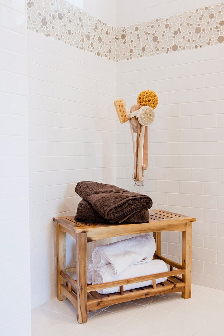 Handtücher & Massagebürsten auf Holztischchen in gefliester Badezimmerecke