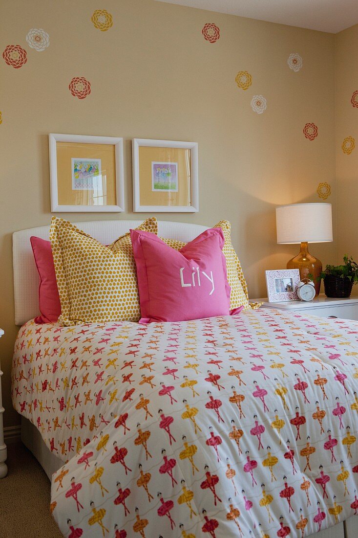 Bett mit Kissen & verspielter Bettwäsche in Pink & Gelb in Mädchenzimmer