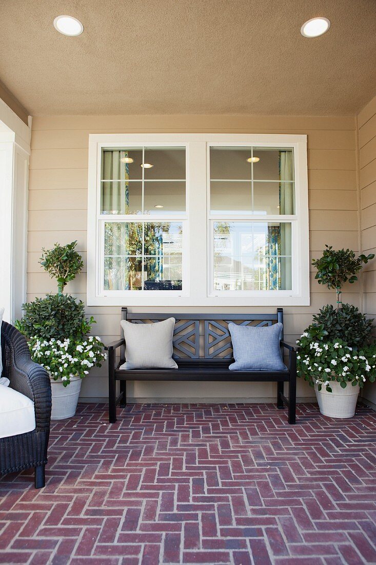 Sitzbank & Kübelpflanzen auf überdachter Veranda mit Ziegelsteinboden