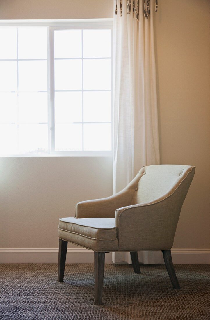 Upholstered armchair below window
