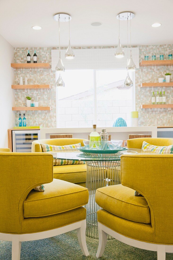 Yellow upholstered armchairs at round table and shelves flanking window