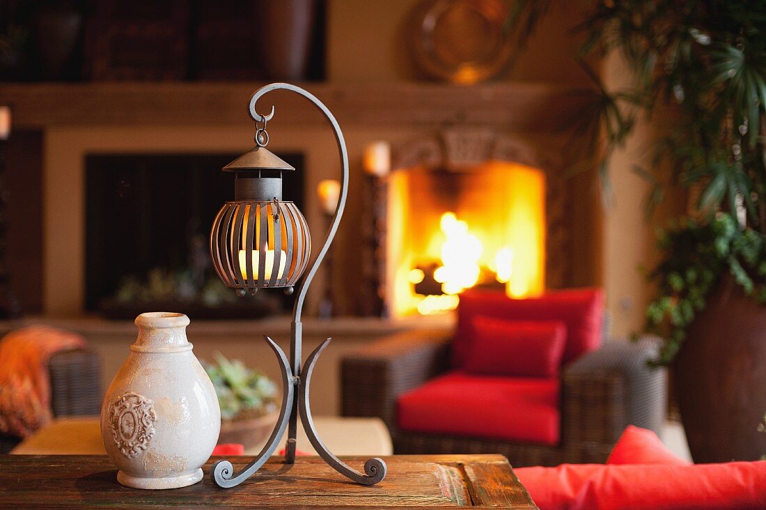 Laterne & Vase auf Tisch in Wohnzimmer mit brennendem Kamin