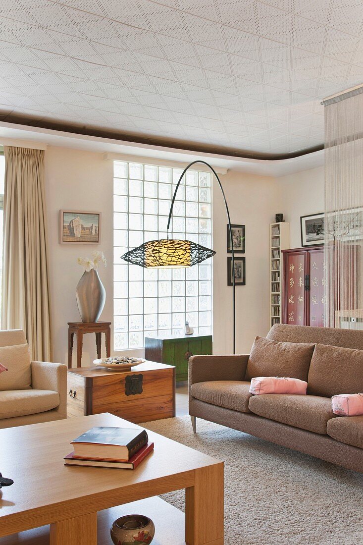 Modernes Wohnzimmer mit Sofa, Bogenleuchte & Glasbausteinwand