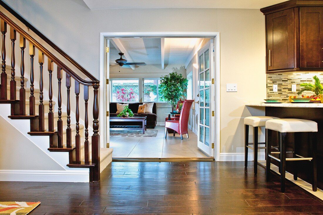 Wohnraum mit Küchentheke, Treppenaufgang & geöffneten Flügeltüren zum Wohnzimmer