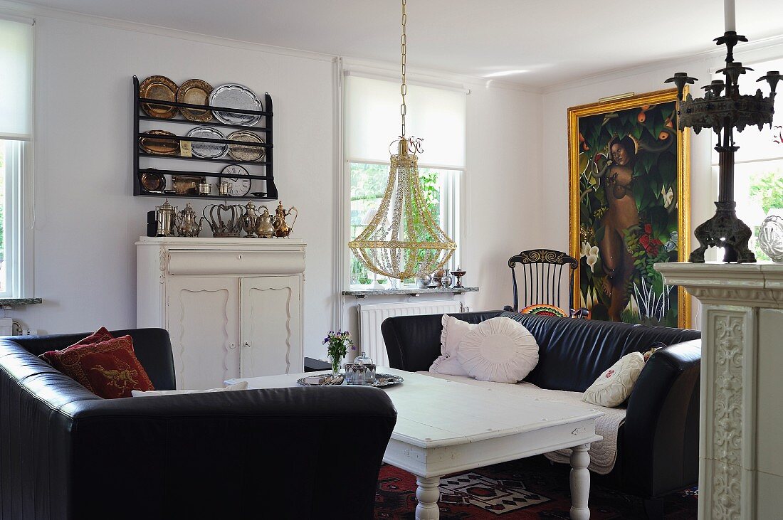 Schwarze Sofas um ländlichen weißen Couchtisch in traditionellem Wohnzimmer
