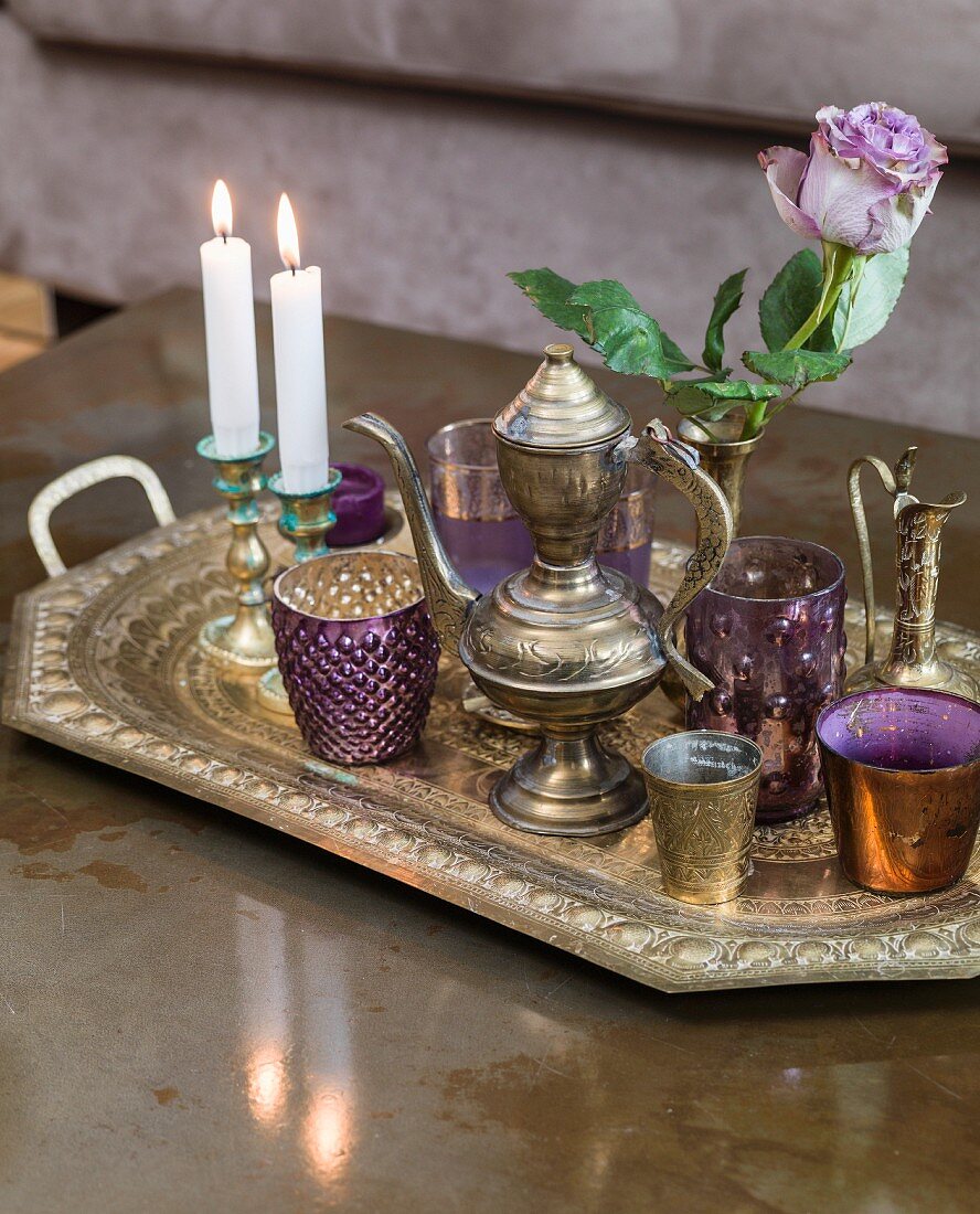 Coated glass beakers, candlesticks and ornate metal jug and teapot on embossed tray