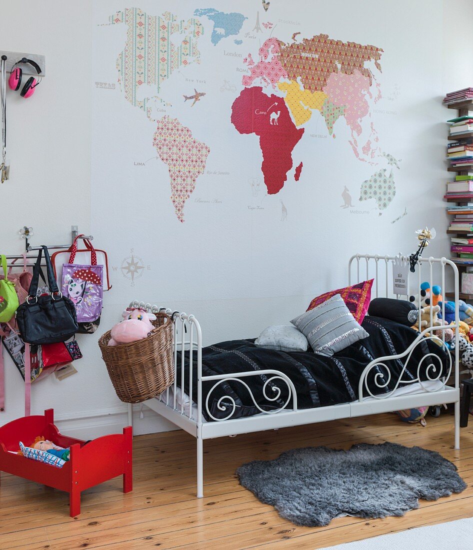 Map of the world in various patterns above metal child's bed