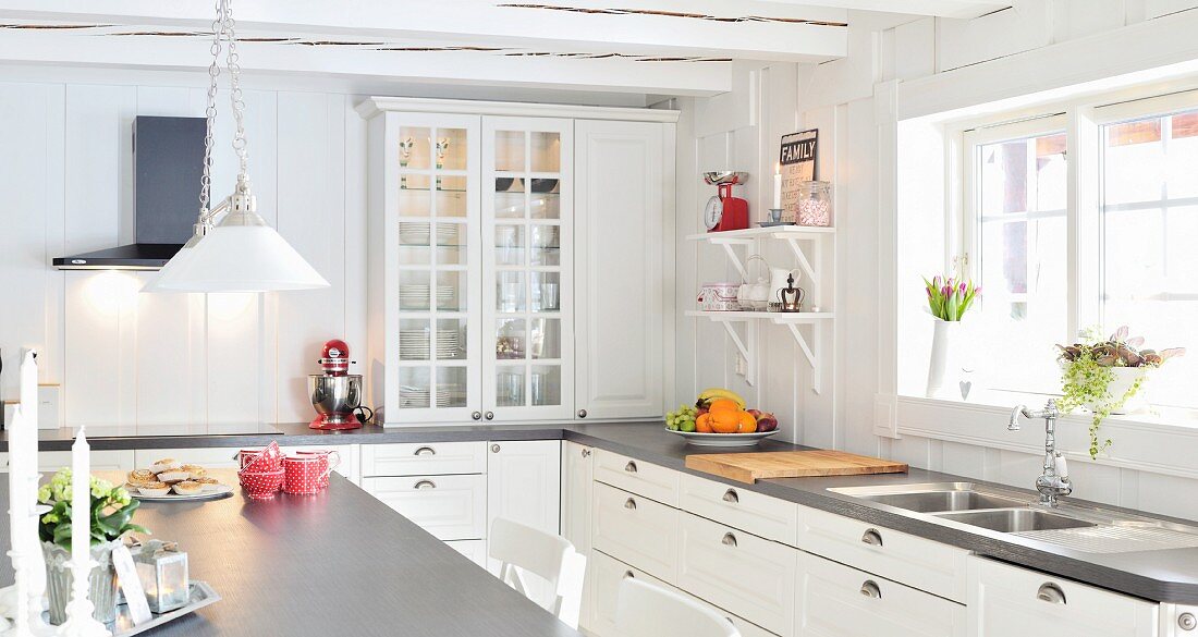 L-shaped, countr-house-style kitchen with white cabinets and grey worksurface in Scandinavian wooden house