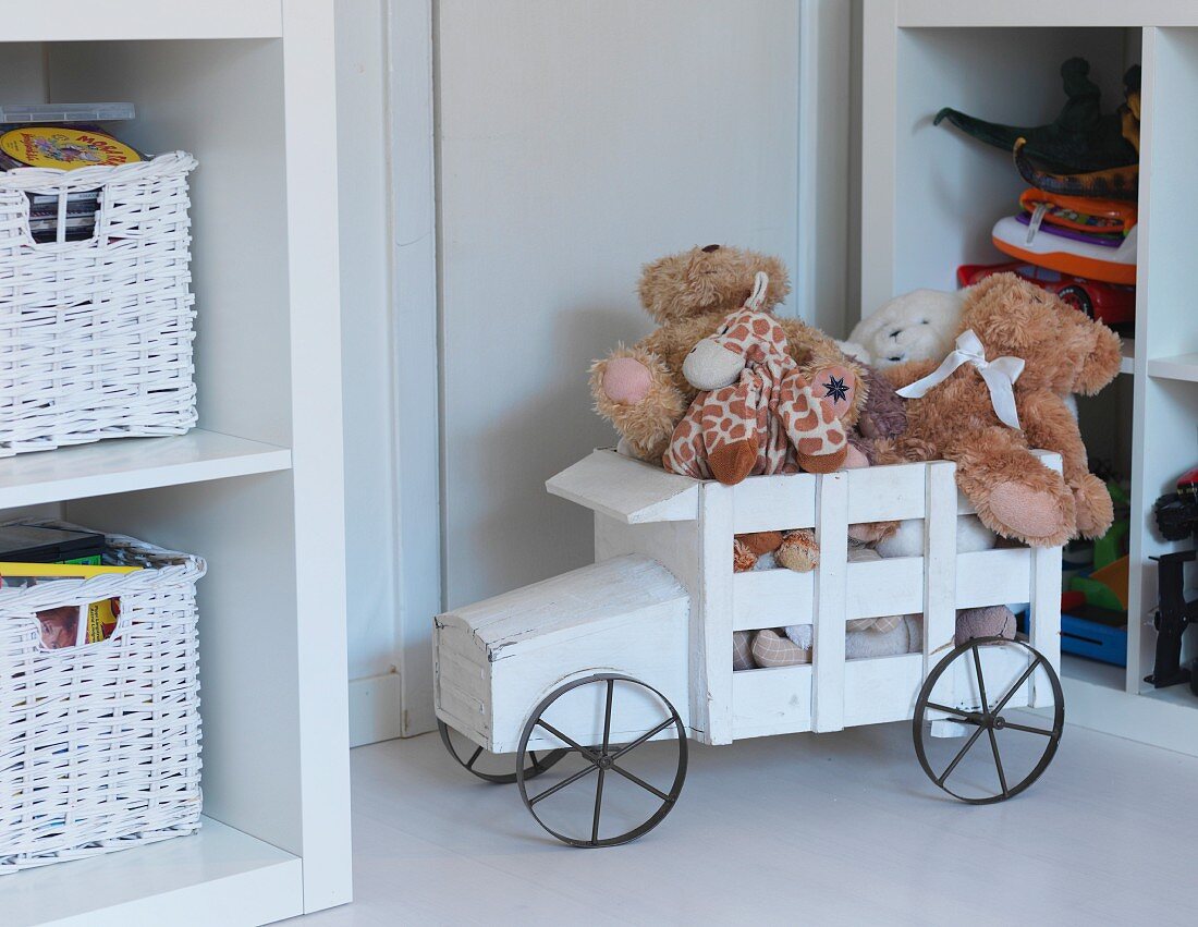 White-painted, rustic, wooden toy truck loaded with soft toys