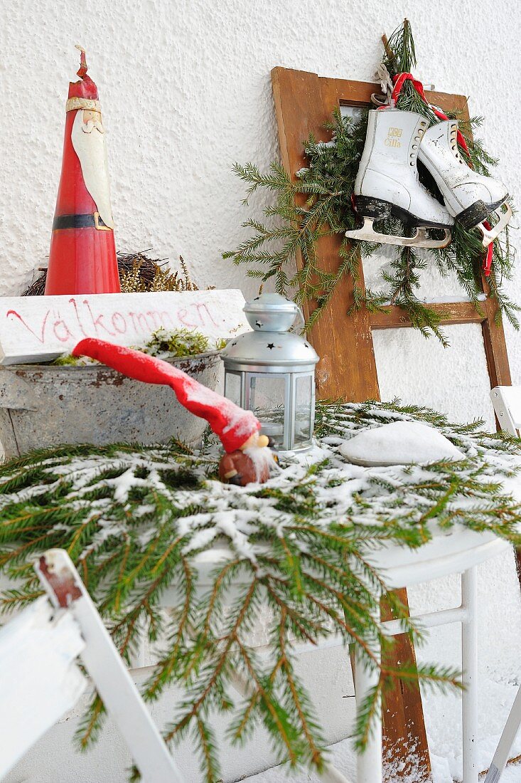 Weihnachtliche Willkommensdeko vor dem Haus mit Weihnachtsfiguren, Laterne und Schlittschuhen auf Tannenzweigen