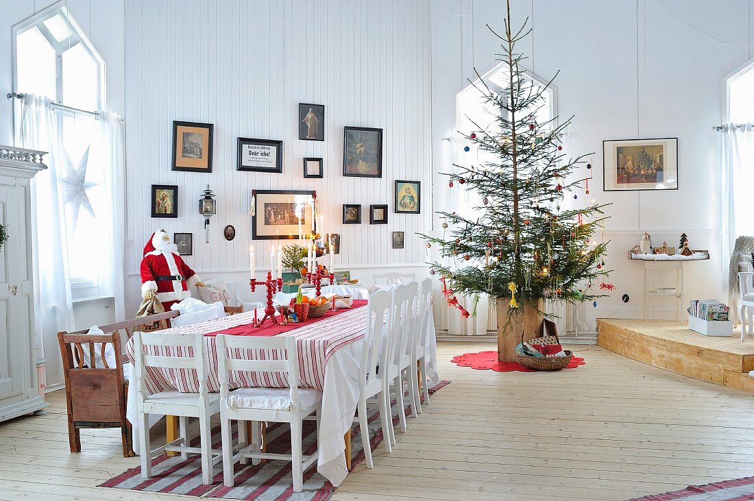 Weihnachtlich dekorierter Esstisch und Christbaum im Wohnraum eines skandinavischen Holzhauses
