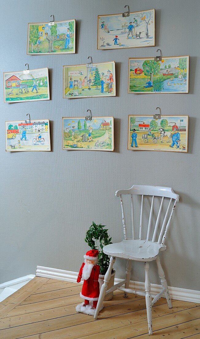 Colourful children's drawings above traditional wooden chair next to Father Christmas figurine at head of staircase