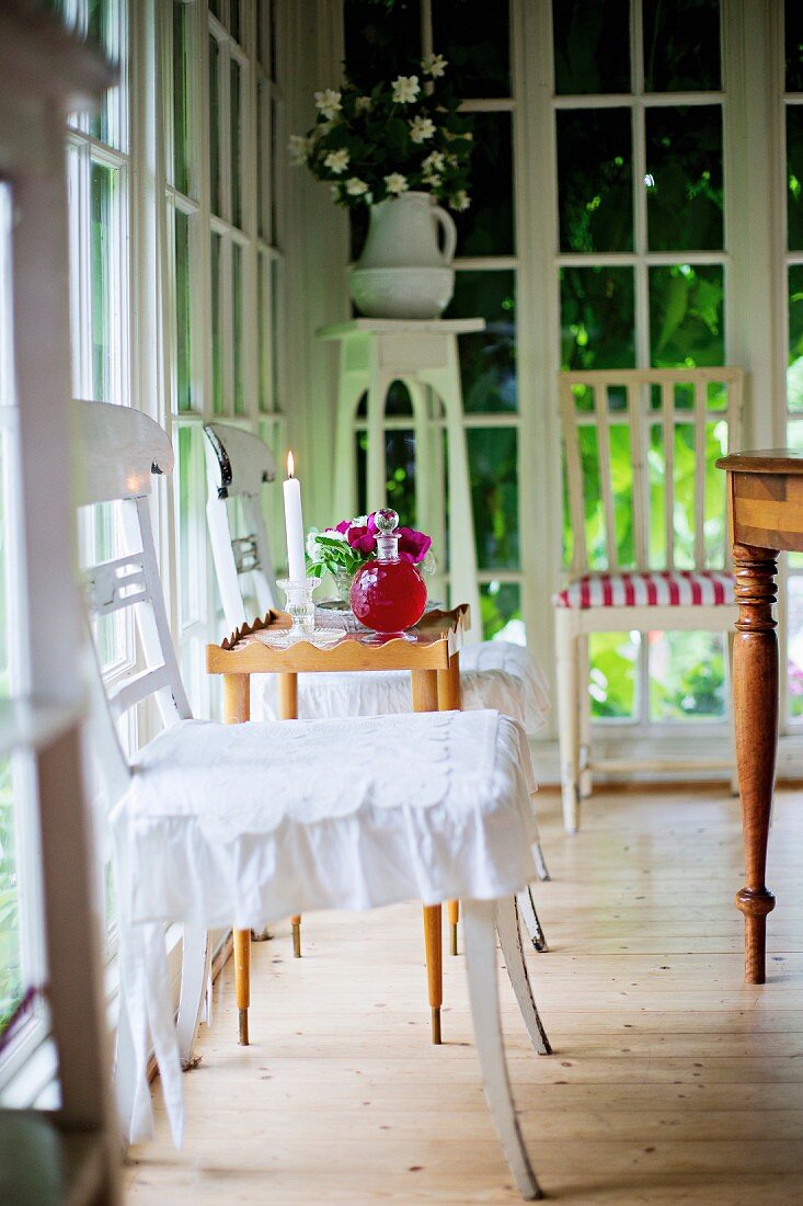 Traditional kitchen chairs painted white in front of floor-to-ceiling lattice windows