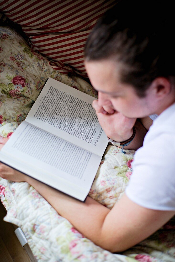 Jugendlicher beim Lesen im Bett