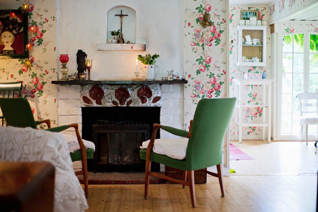 50s armchairs with green upholstery in front of open fireplace in rustic interior