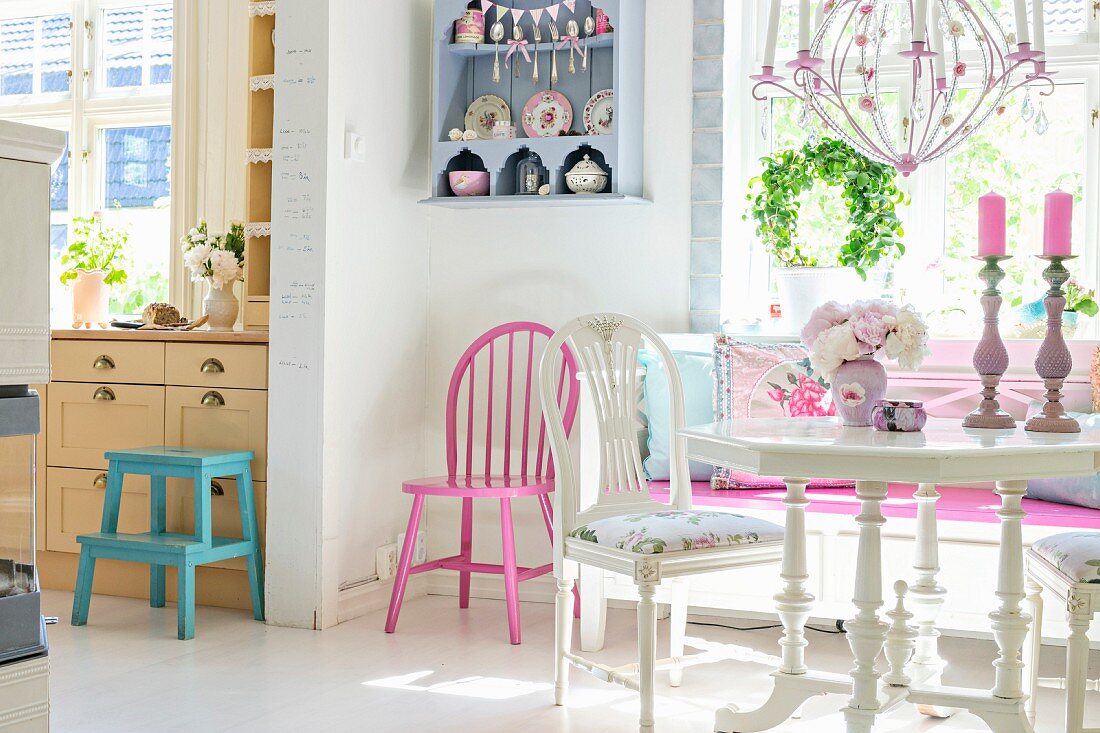 Nostalgischer Essplatz in Weiß, gegenüber Durchgang zur Küche, in der Ecke rosa lackierter Stuhl