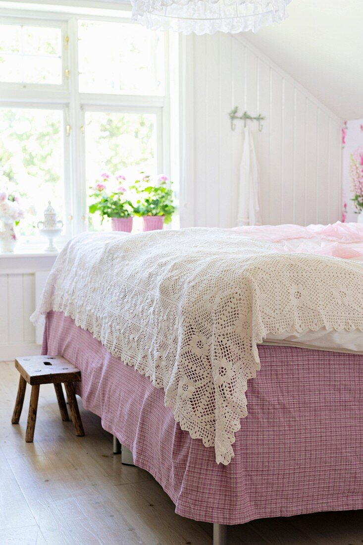 Crocheted, white bedspread on double bed in rustic bedroom