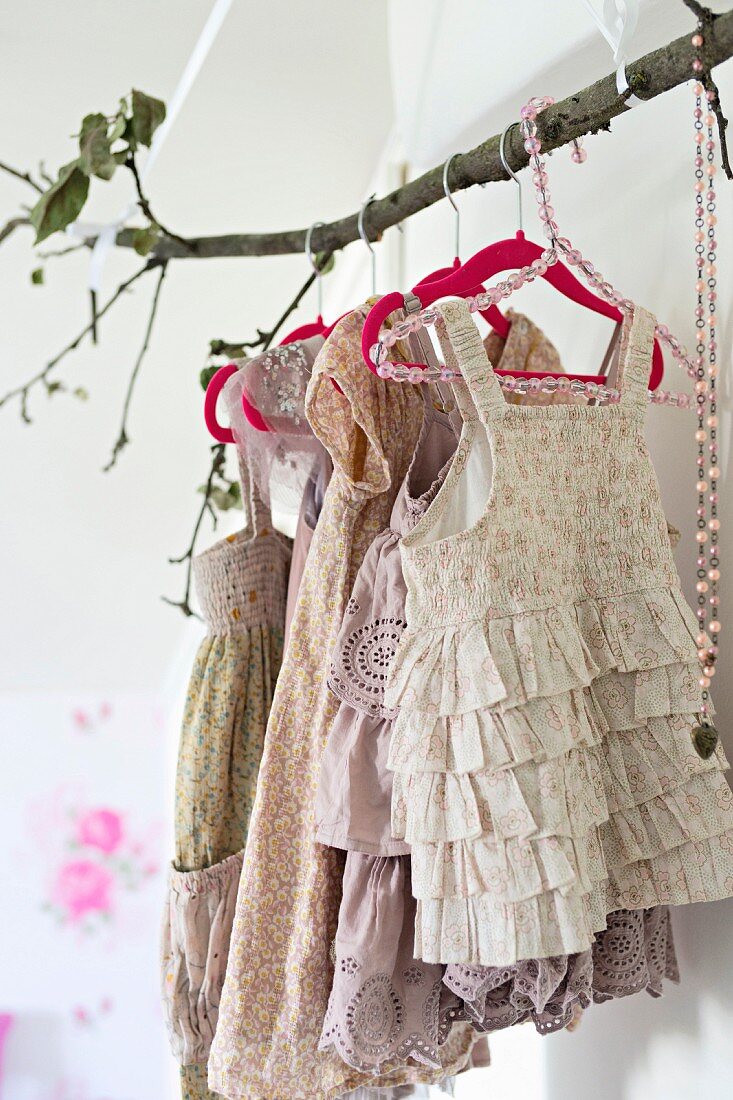 Branch used as clothes rack holding vintage-style girl's clothing