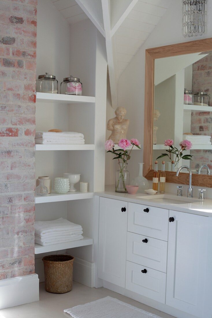 Weisses Einbau Regal und Waschtisch in Massanfertigung vor gerahmtem Spiegel an Wand in Badezimmerecke