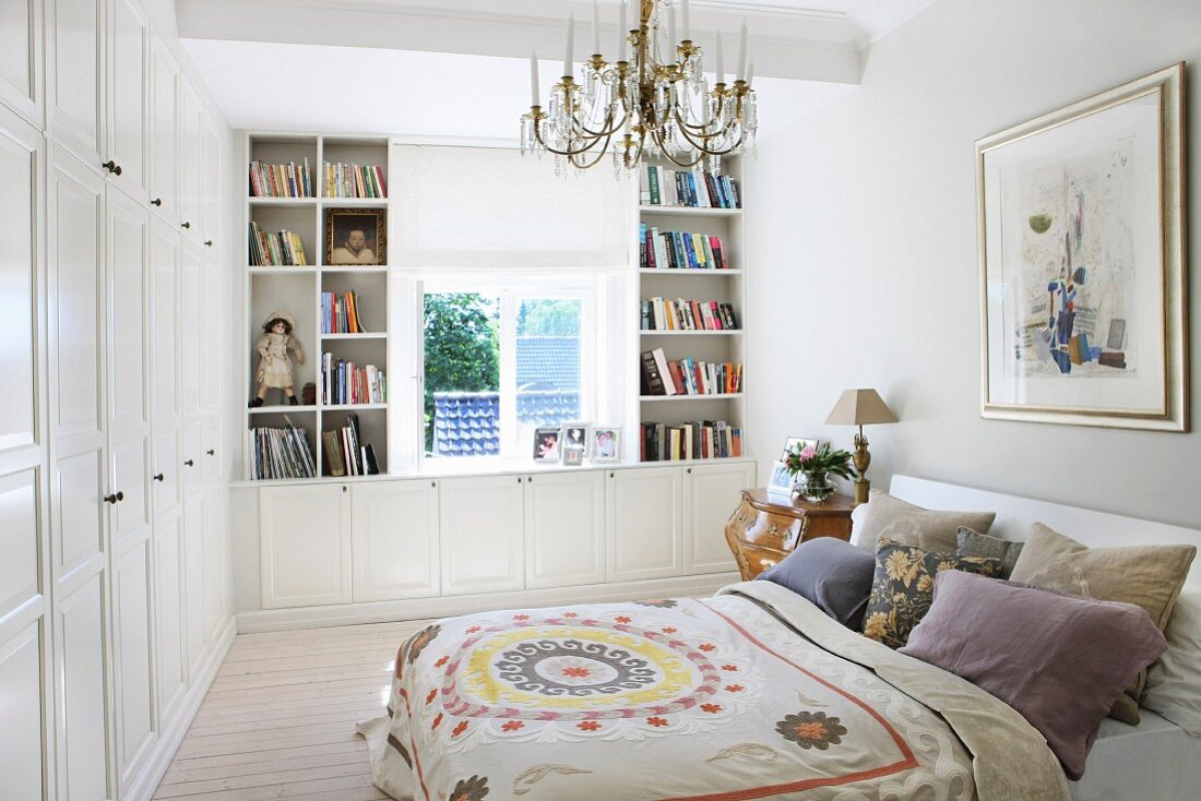 Doppelbett mit gemusterter Tagesdecke und Kissenstapel in ländlichem Schlafzimmer, mit massgefertigten Schränken und Regalen in Weiß