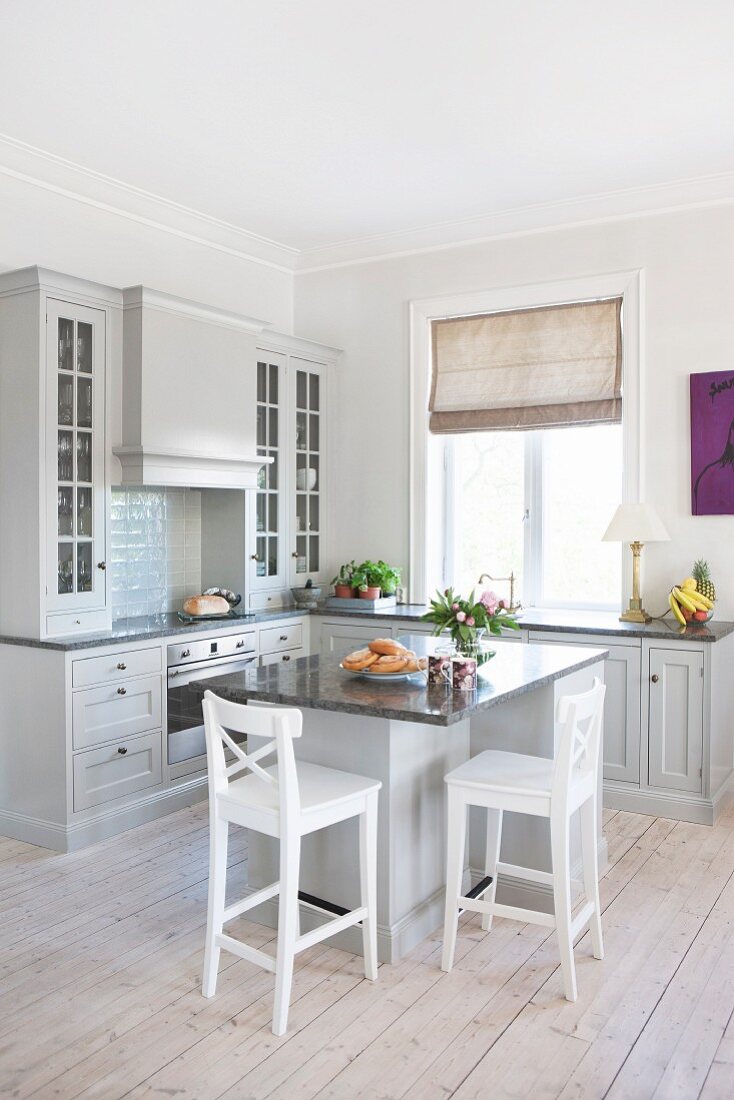 Island counter and white bar stools in open-plan, country-house kitchen