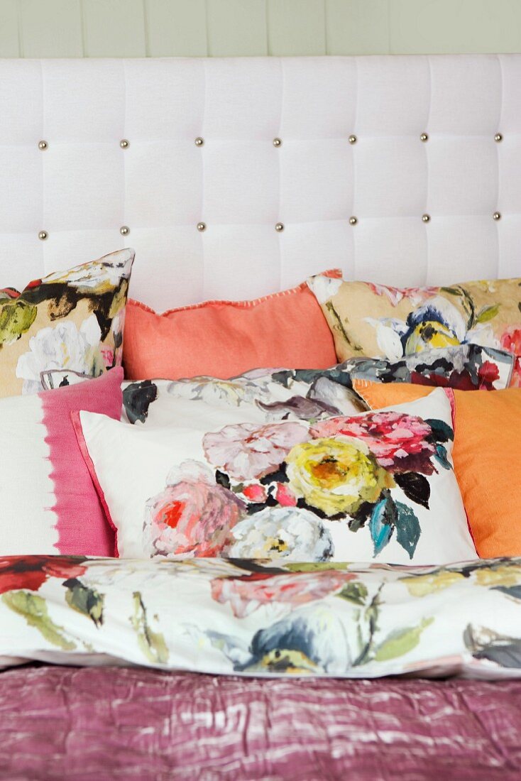 Kissenbezüge mit floralen Prints zu abgestimmten Unifarben und weißes Bettkopfteil mit Polsterknöpfen