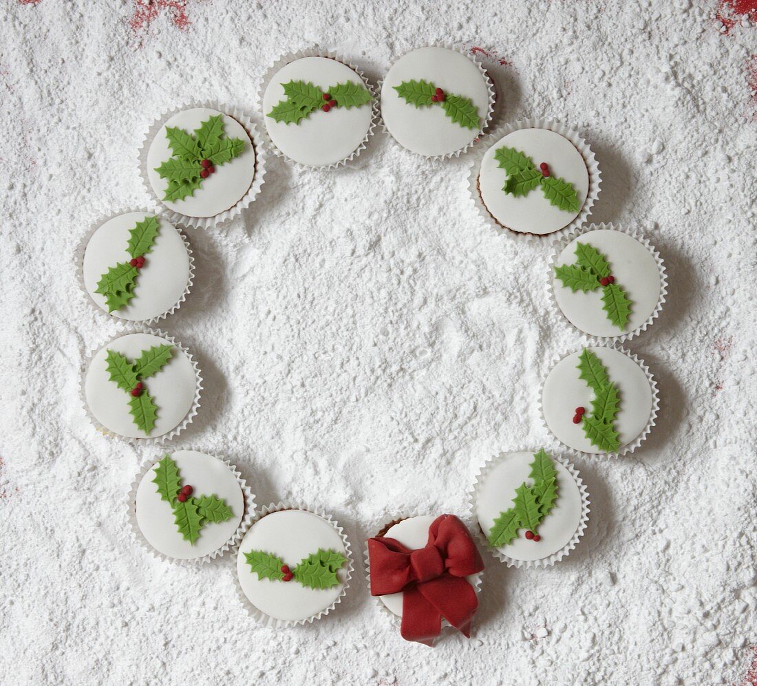 Kranz aus weihnachtlich verzierten Cupcakes auf weißem Untergrund