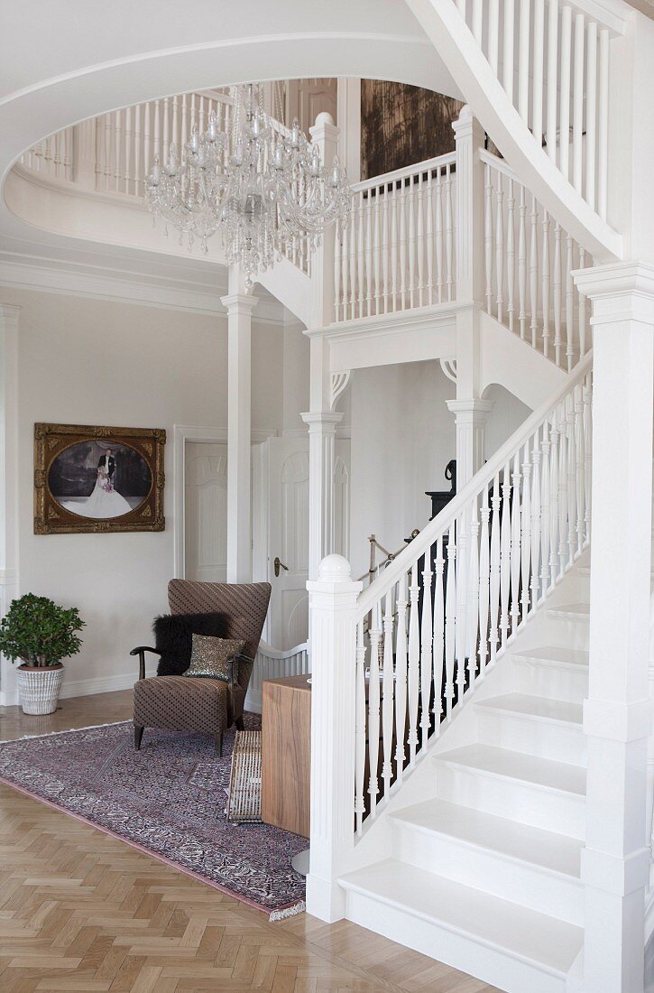Staircase with white-painted, wooden balustrade in foyer of villa
