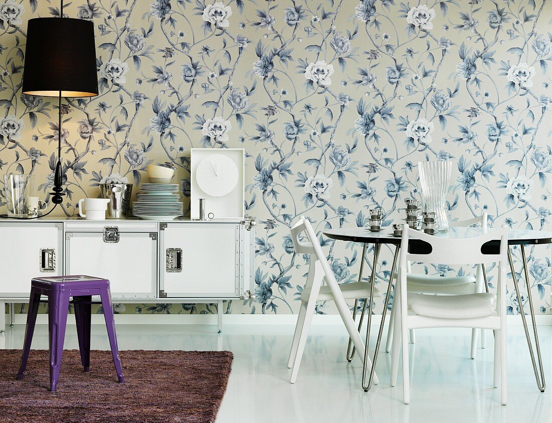 Tisch mit Stühlen und Sideboard in Esszimmer mit floral gemusterter Tapete