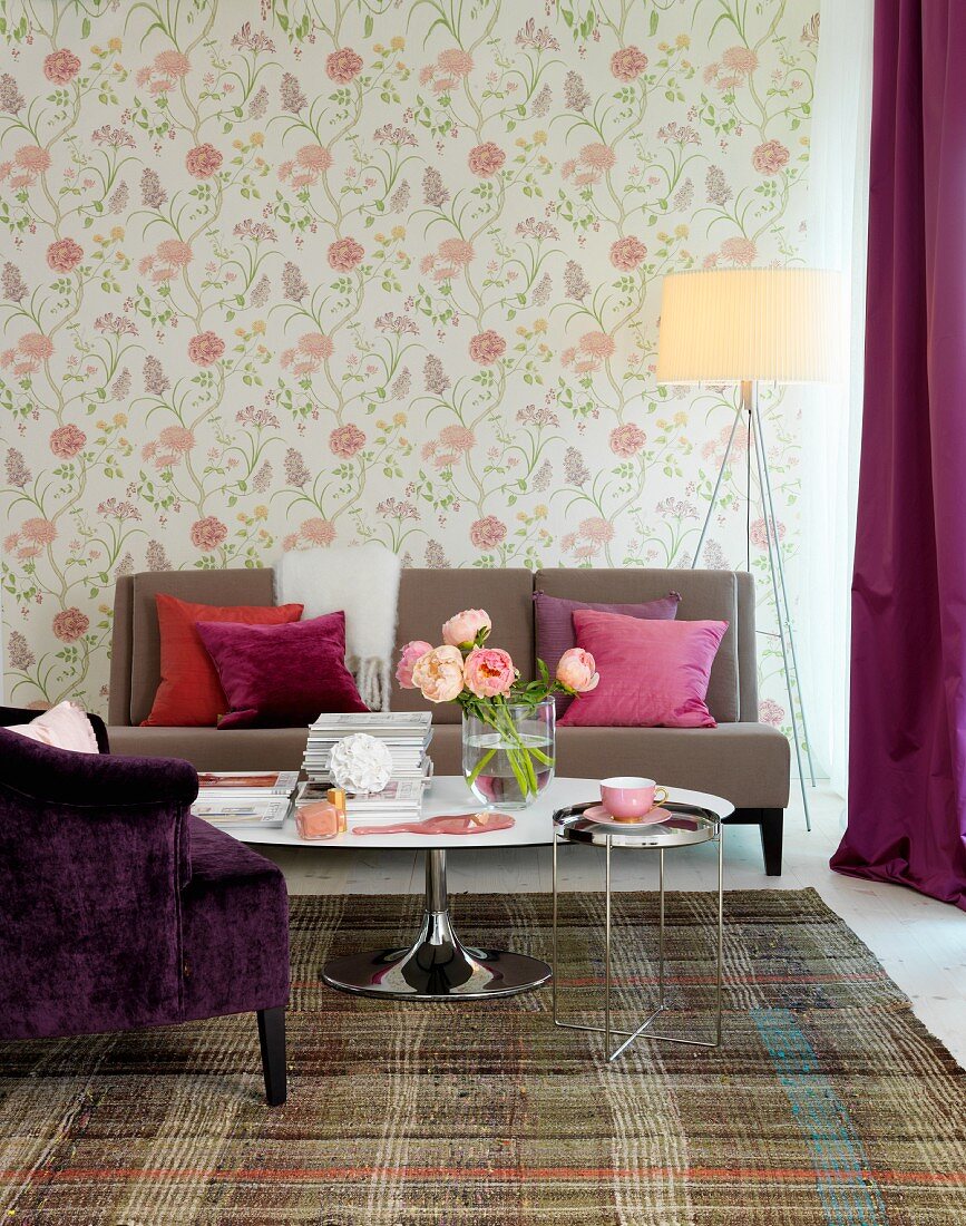 Tulip Couchtisch und hellbraune Couch vor Wand mit floraler Tapete in Pastelltönen, seitlich Stehleuchte