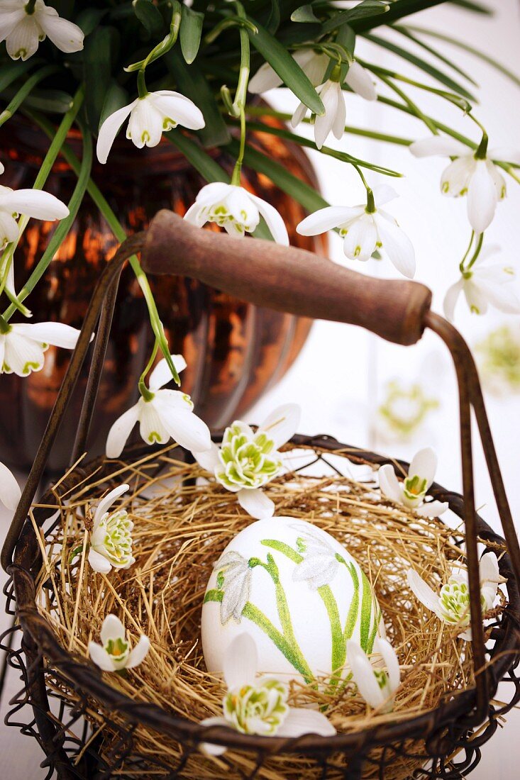 Easter egg decorated with snowdrops using napkin decoupage in small basket