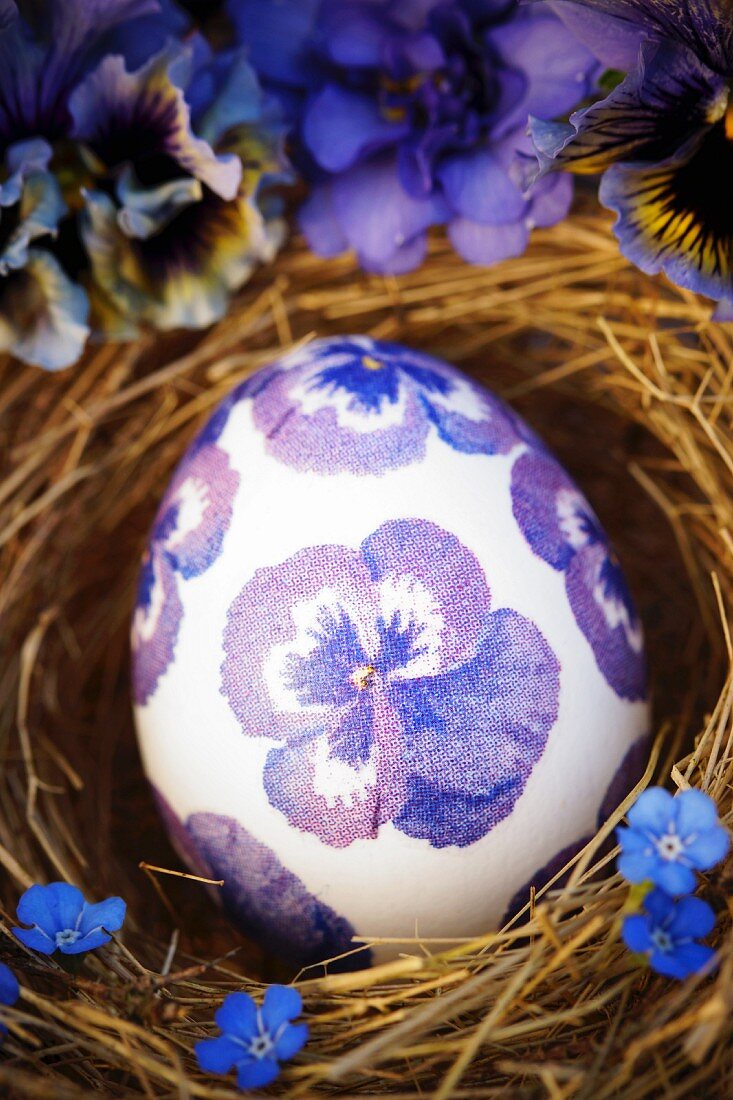 Osterei mit blauen Hornveilchenblüten in Serviettentechnik dekoriert