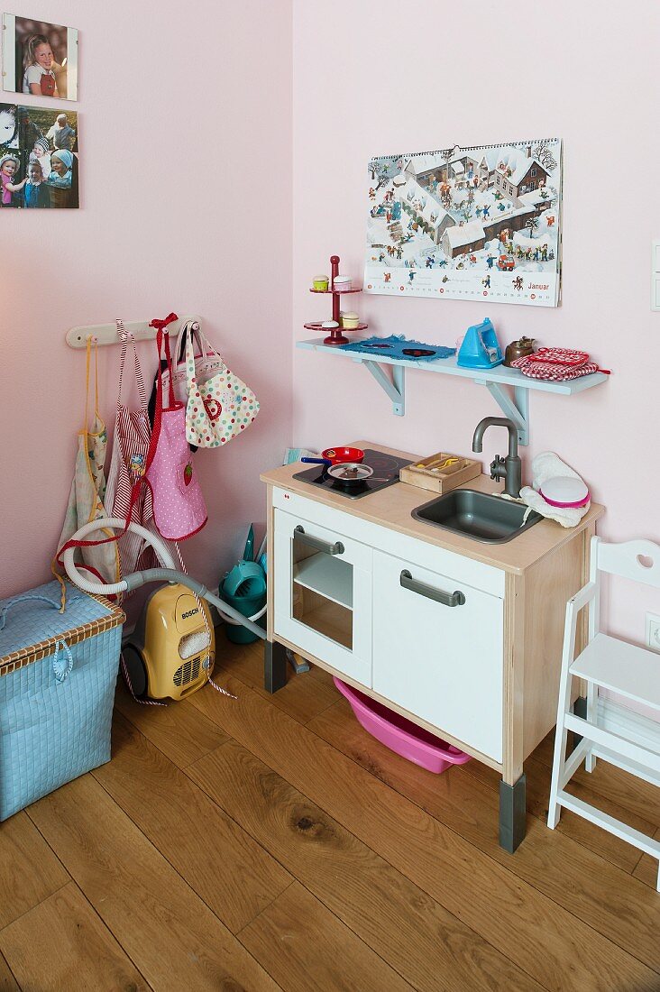 Kinderküche und blau lackierte Wandkonsole an rosa getönter Wand in Kinderzimmerecke