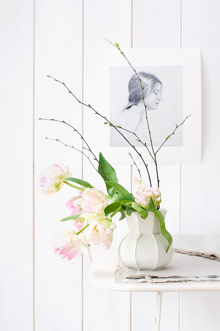 Papageientulpen in weisser Retro Vase, vor weisser Holzwand mit aufgehängter Zeichnung