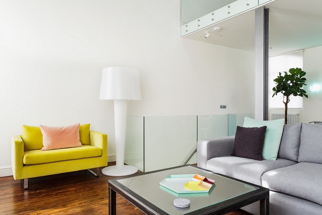 Loungebereich mit hellgrauem Couch, gelbem Polstersessel und Stehlampe im Designerstil