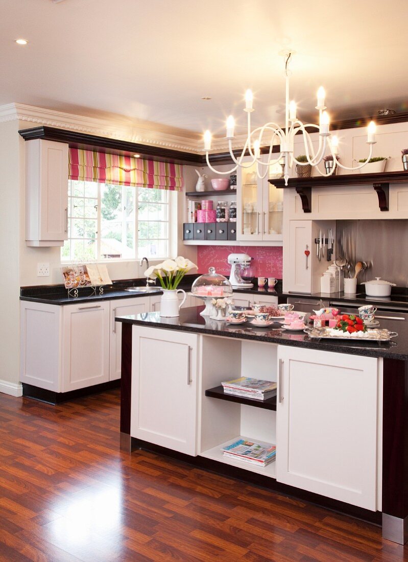 Schwarz-weiße Einbauküche mit gestreiftem Faltrollo und pinkfarbenem Spritzschutz