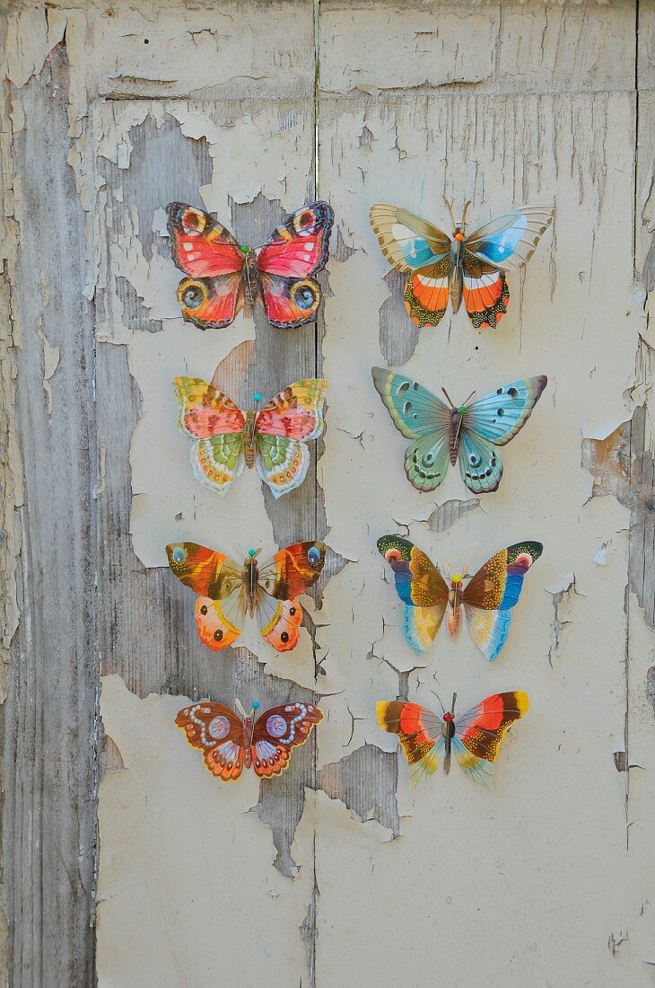 Colourful paper butterflies on wooden board with peeling paint