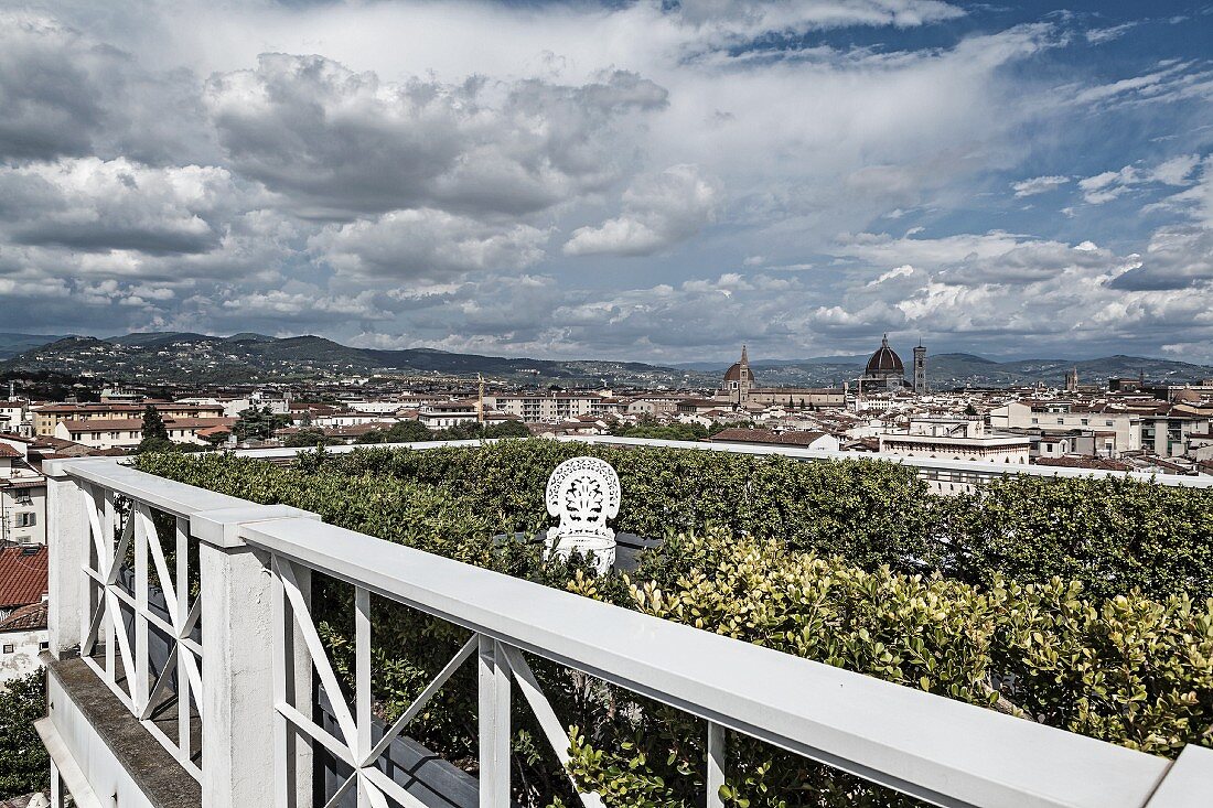 Blick über Dachterrasse mit umlaufender Heckenbepflanzung vor weißer Brüstung im Hintergrund Blick auf Florenz
