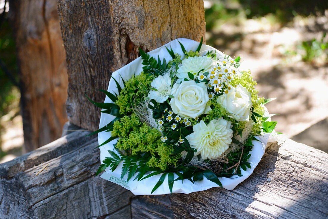 Summery bouquet with white roses (roses, dahlias, chamomile, lady's mantle) on rust wooden balustrade