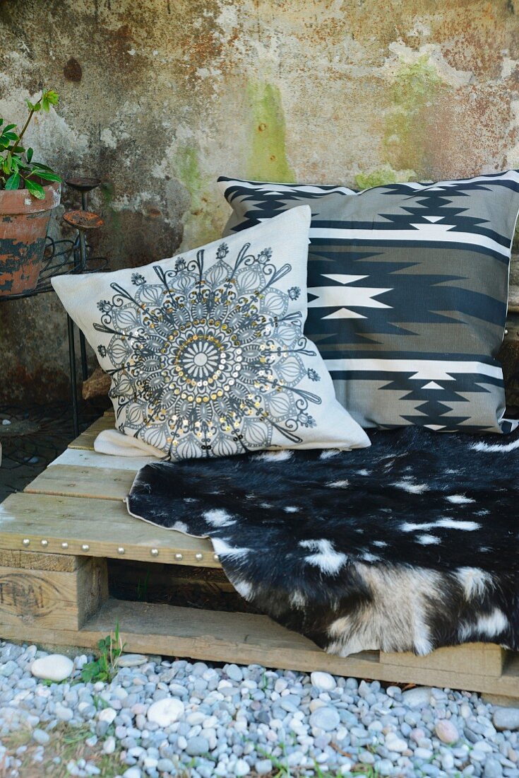 Bench made from old wooden pallet with goat-skin blanket and ethnic-style cushion