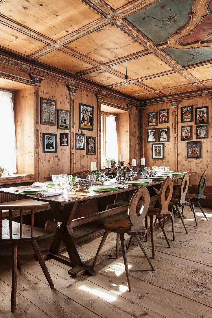 Festively set table in wood-panelled dining room of Italian chalet with antique, farmhouse furnishings