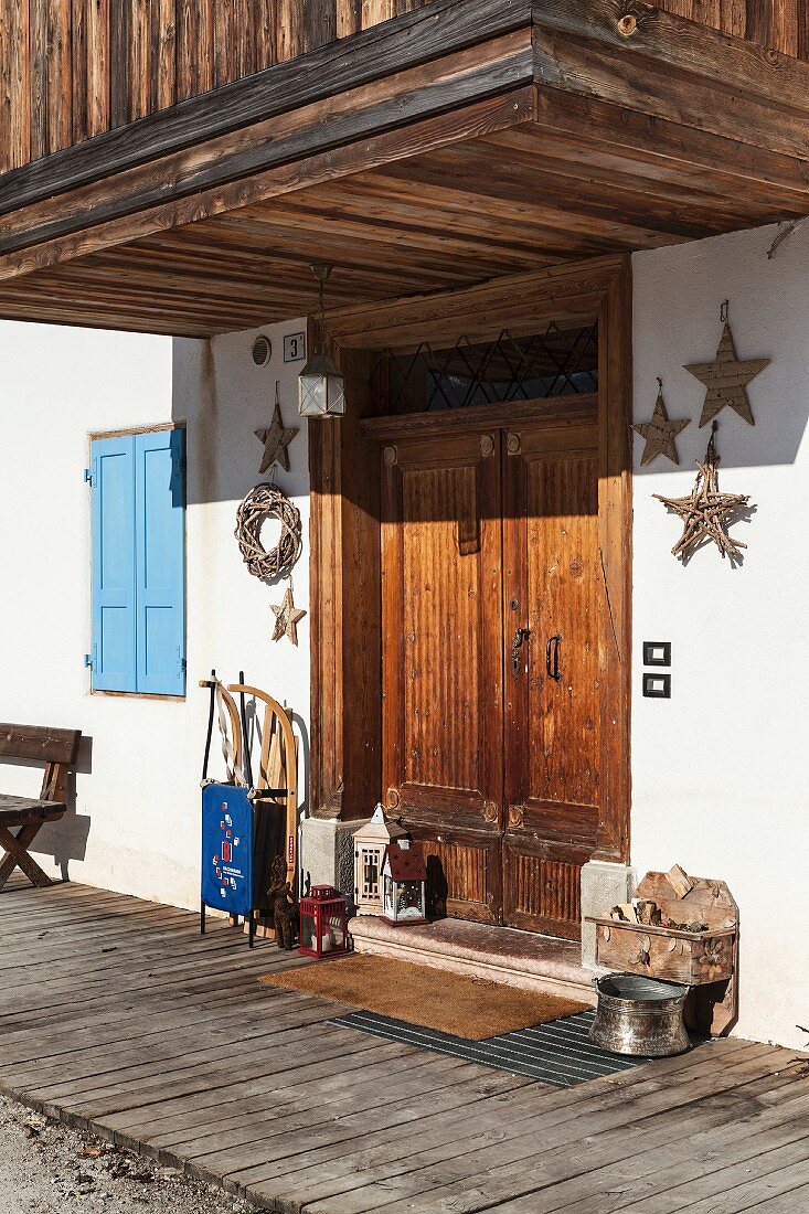Schlitten, Laternen und Stern-Deko vor der Haustür eines historischen italienischen Chalets